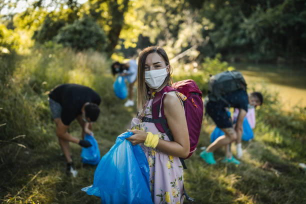 giovani volontari che raccolgono rifiuti dalla riva del fiume - trash day foto e immagini stock