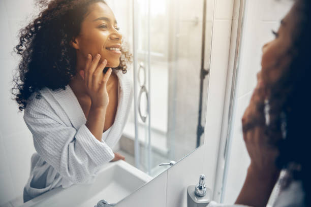 pleased lady in a bathrobe staring at her reflection - mirror women looking reflection imagens e fotografias de stock