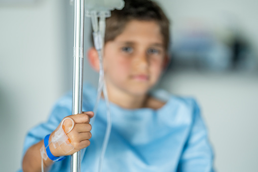 Close up of a young boy sitting in the hospital with an IV drip