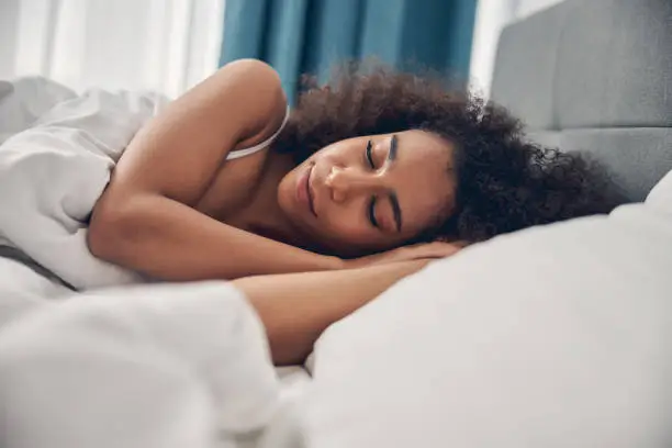 Photo of Serene curly-headed female lying on the pillow