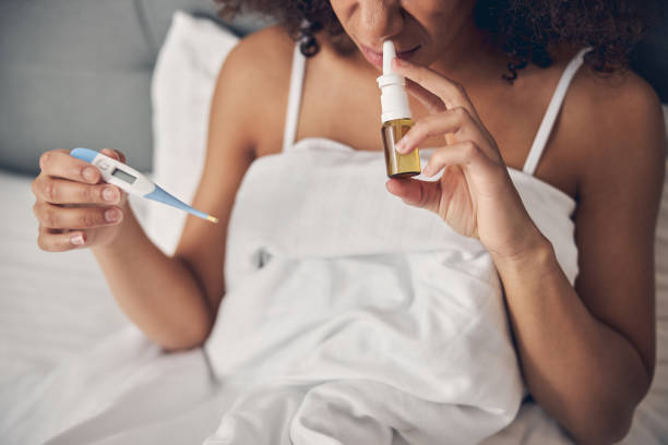 istock Woman with a digital thermometer sitting in bed 1256774318