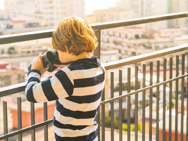 istock Blonde boy with binoculars exploring the city 1256776888