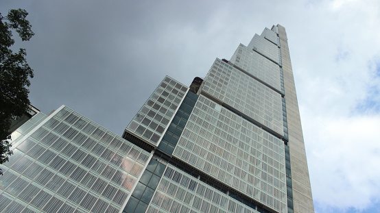 Low angle view of the tallest skyscraper of Bogotá and Colombia: BD Bacatá, designed as big blocks with blue windows and a stormy cloudy sky during the colombian winter