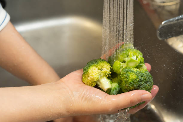 lavare i broccoli nell'acqua che versa - leek green raw food foto e immagini stock