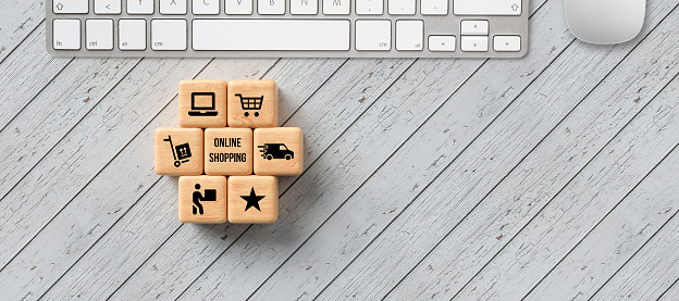 cubes with message ONLINE SHOPPING and shopping cart symbols on wooden background