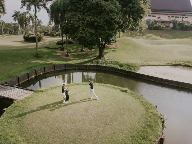 A peaceful image of a golf course green featuring a hole with a yellow flag, surrounded by lush green grass and scenic palm trees. The image evokes a sense of calm, leisure, and the beauty of nature. Perfect for use in travel, sports, or landscape related projects.