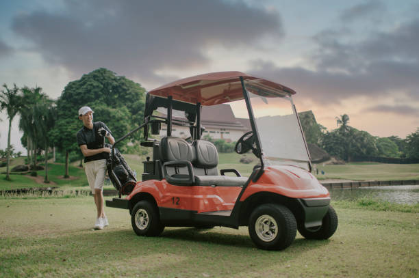 ゴルフカートからゴルフバッグを運び、ティーポイントまで歩いてゴルフゲームを始めるアジアの中国のティーンエイジャーの少年 - golf cart golf bag horizontal outdoors ストックフォトと画像