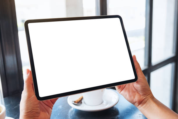 istock a woman holding black tablet pc with blank white screen with coffee cup on the table 1256802531