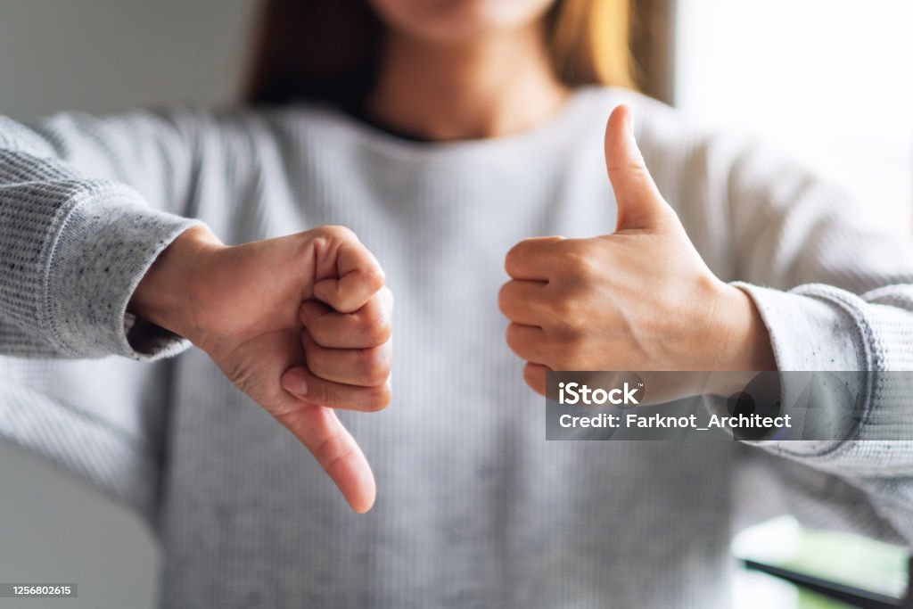 a woman making thumbs up and thumbs down hands sign Closeup image of a woman making thumbs up and thumbs down hands sign Feedback Stock Photo