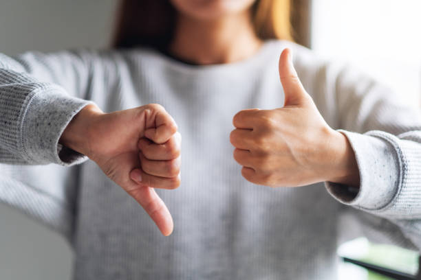 a woman making thumbs up and thumbs down hands sign Closeup image of a woman making thumbs up and thumbs down hands sign negative emotion stock pictures, royalty-free photos & images