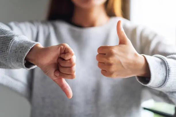 Photo of a woman making thumbs up and thumbs down hands sign