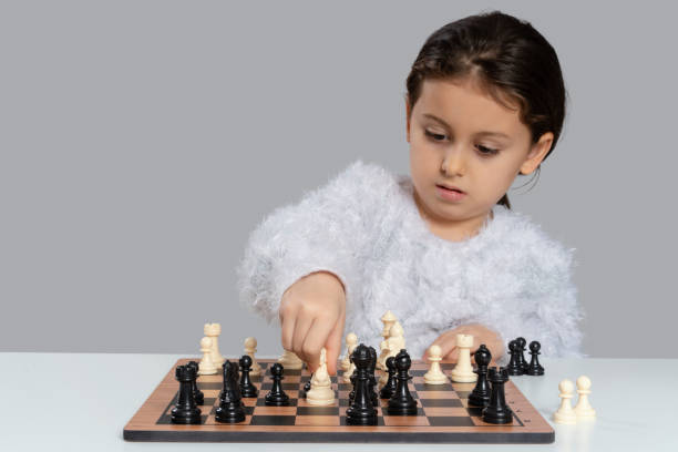 istock Little girl playing chess, gray background 1256806035