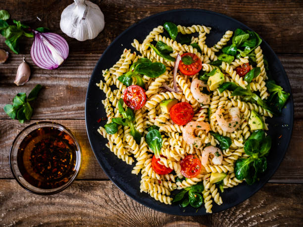 istock Pasta with prawns and vegetables on wooden background 1256806890