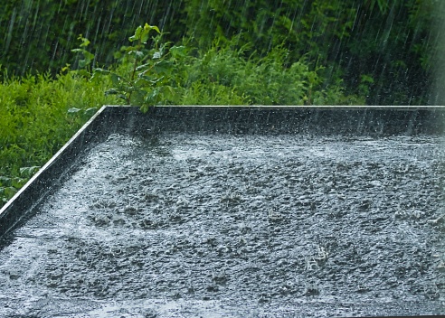 Heavy rain on a black flat roof against a green background