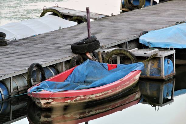 istock Red rowboot with blue tarpaulin on wooden jetty 1256809848