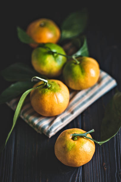 Tangerines with leaves on an old fashioned country table. Selective focus. Vertical. Background with copy space.