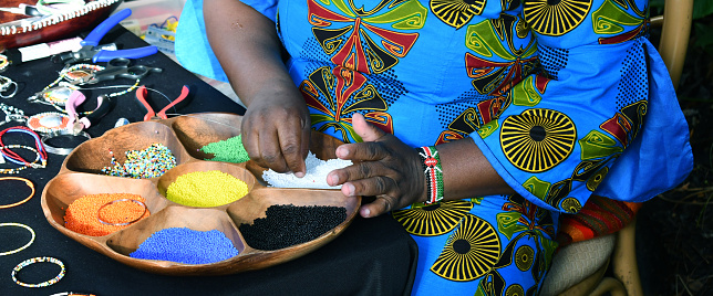 African lady creating beaded necklaces