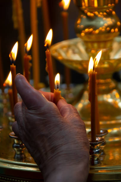 istock Old hand lights a candle in a church 1256815778