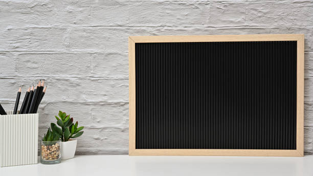 Office creative desk with letter board on white table and white brick wall. Front view