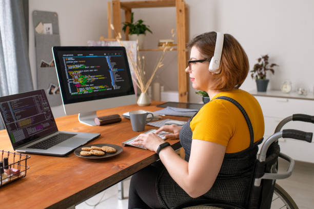 istock Young pretty female software developer in wheelchair working with data at home 1256819033