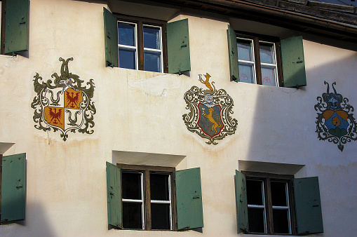 Guarda, Switzerland - Aug 14, 2009: Facade of an ancient house with windows and coat of arms in the small village of Guarda, Scuol municipality, Engadin valley, Graubunden canton, Switzerland, Europe