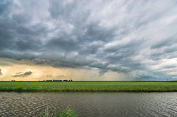 Storm clouds over wide open flat dutch landscape at sunset.
