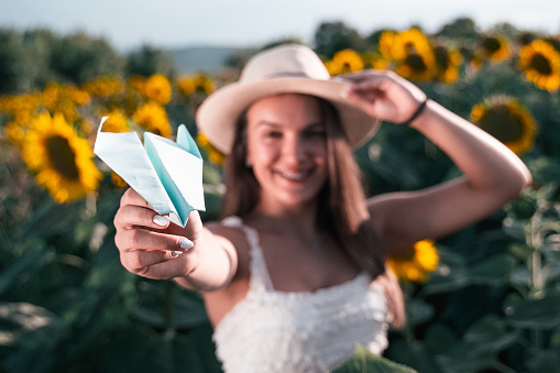 Eco tourism in the sunflower fields. Getting away from it all, explore nature. Young woman dressed in white, enjoying the blooming sunflowers and the idea of traveling abroad. Vacation time.
