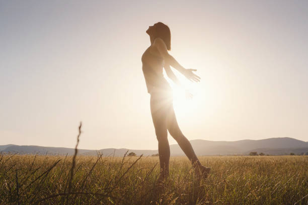 istock Young girl spreading hands with joy and inspiration facing the sun 1256826557