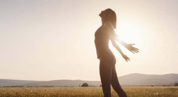 istock Young girl spreading hands with joy and inspiration facing the sun 1256826607