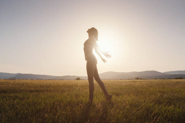 istock Young girl spreading hands with joy and inspiration facing the sun 1256826628