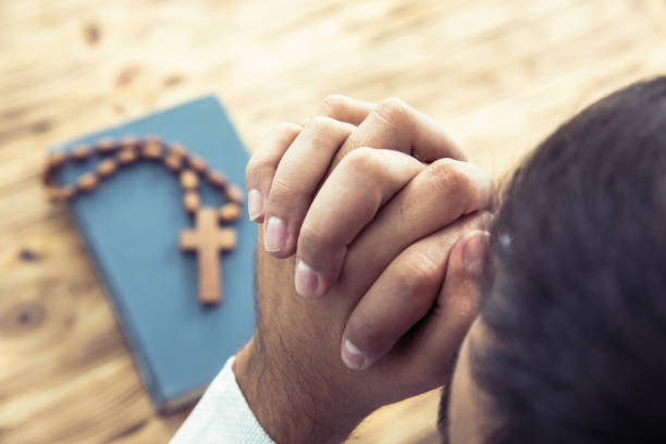istock Prayerful man hand cross and Bible 1256826762