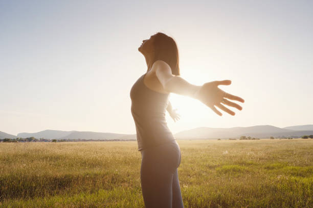 istock Young girl spreading hands with joy and inspiration facing the sun 1256826776