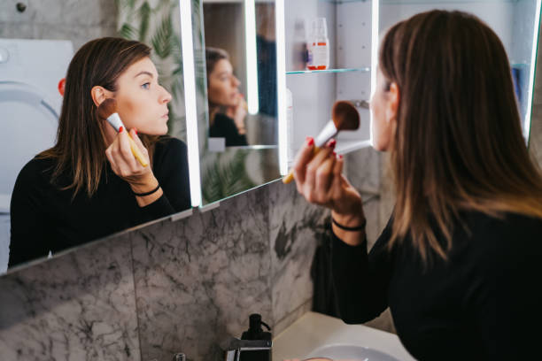 istock Young woman applying make up 1256832061