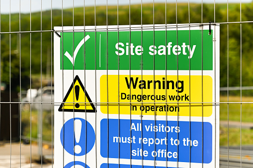 Safety signs on a wire fence around a construction site