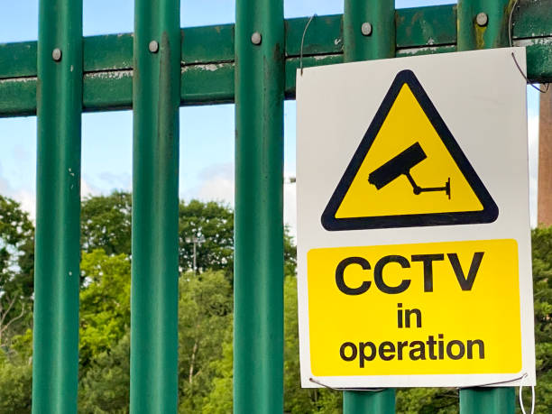 Sign on a fence warning of CCTV surveillance Close up view of a notice on a metal fence stating CCTV recording is in use. surveillance camera sign stock pictures, royalty-free photos & images
