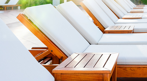 Blank white wooden loungers in a row in luxury hotel. Sunbed for sunbathing in the inn.