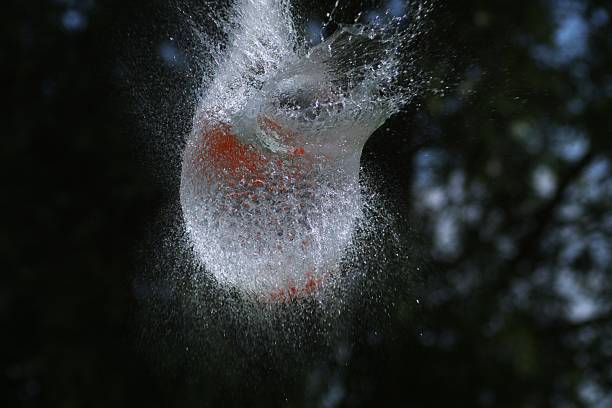 istock Shot Breaking Water Filled Orange Balloon 1256834570