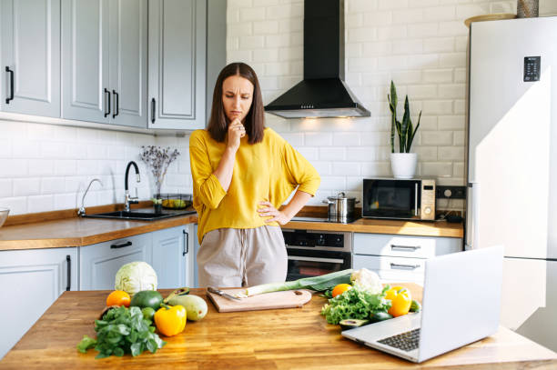 istock A woman is cooking, a laptop on the table 1256836150
