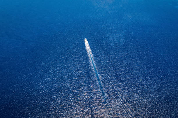 Aerial view of a motorboat travelling over blue, mediterranean sea Aerial view of a motorboat travelling over blue, mediterranean sea in Greece , with copy space sea wake stock pictures, royalty-free photos & images