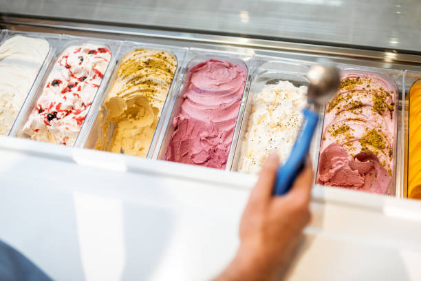 istock Salesman picking ice cream with a spoon from refrigerator in the shop 1256837272