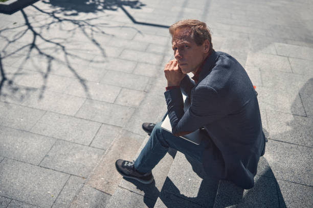 istock Good-looking man sitting on steps on the street 1256842863