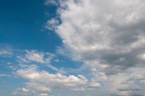 White clouds hover slowly through the blue skyscape. They prvovide shade on a hot summer day. A sky only, full-frame and close-up image.