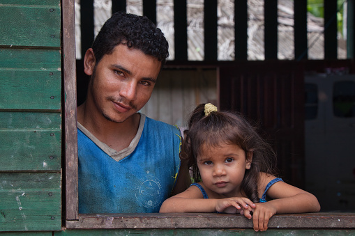 A man and his young daughter pose for the camera in the window of their home in Macapa in Amapa State, Brazil