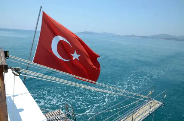 Turkey flag waving in the wind on a sea background. Turkish flag on board ship. Turkey Summer Vacation Concept.