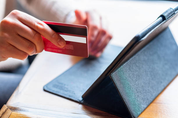 istock Close-up woman's hands holding a credit card and using tablet. 1256848339