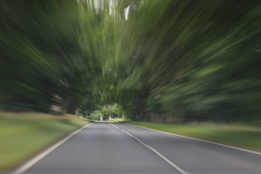 A blurred long exposure shot of a road taking from a moving vehicle.