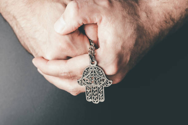 close-up de mãos dobradas segurando amuleto hamsa também conhecido como mão de fátima - hamsa - fotografias e filmes do acervo