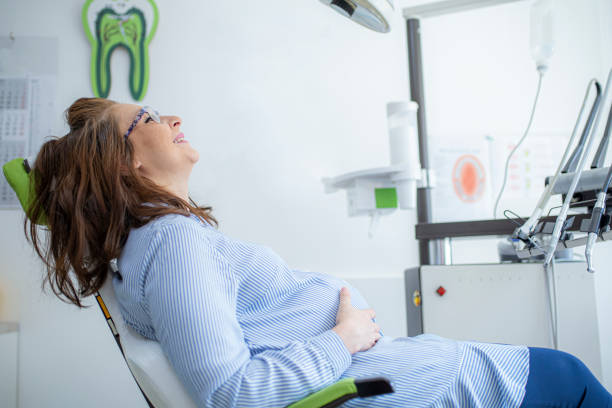 mulher grávida sorrindo durante seu check-up no dentista - dentists chair anticipation smiling healthcare and medicine - fotografias e filmes do acervo