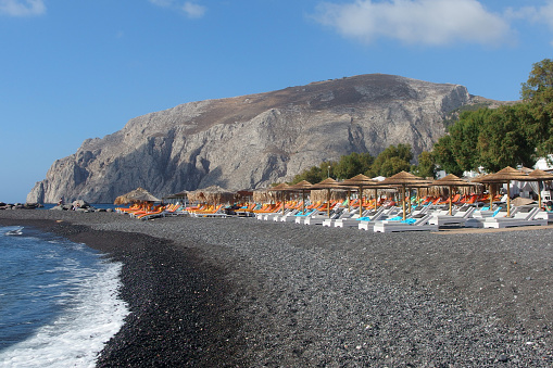 volcanic beach in Kamari town on Santorini with blue sky in the background