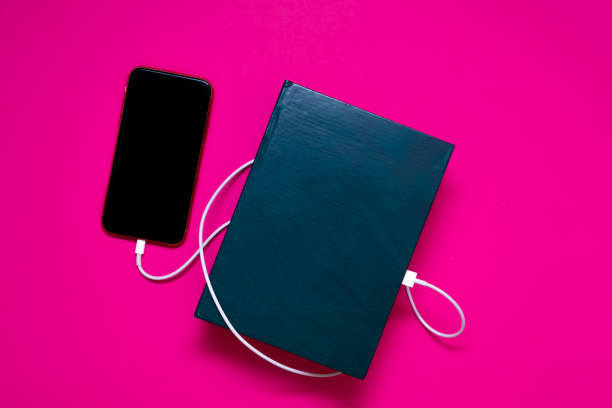 istock Smart phone connected to the old book with a cable, and download information from there 1256853241